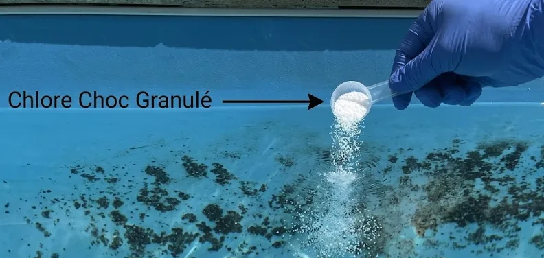 Main gantée versant du chlore choc granulé directement sur une tache de liner immergée — test de diagnostic